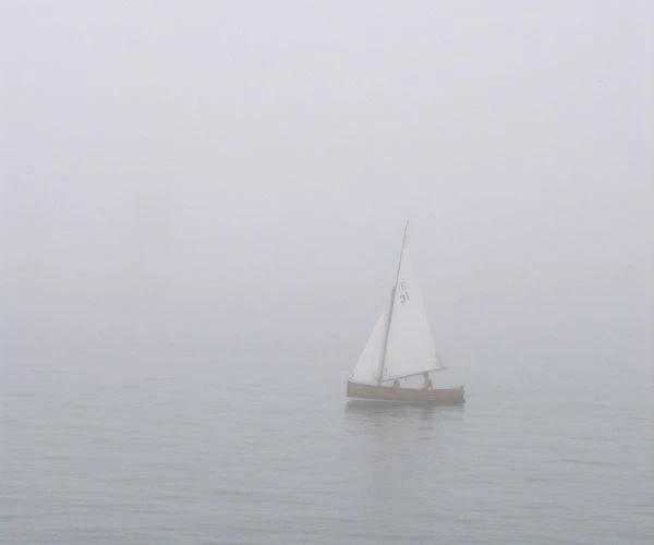 A Sailboat Is Underway in the Fog